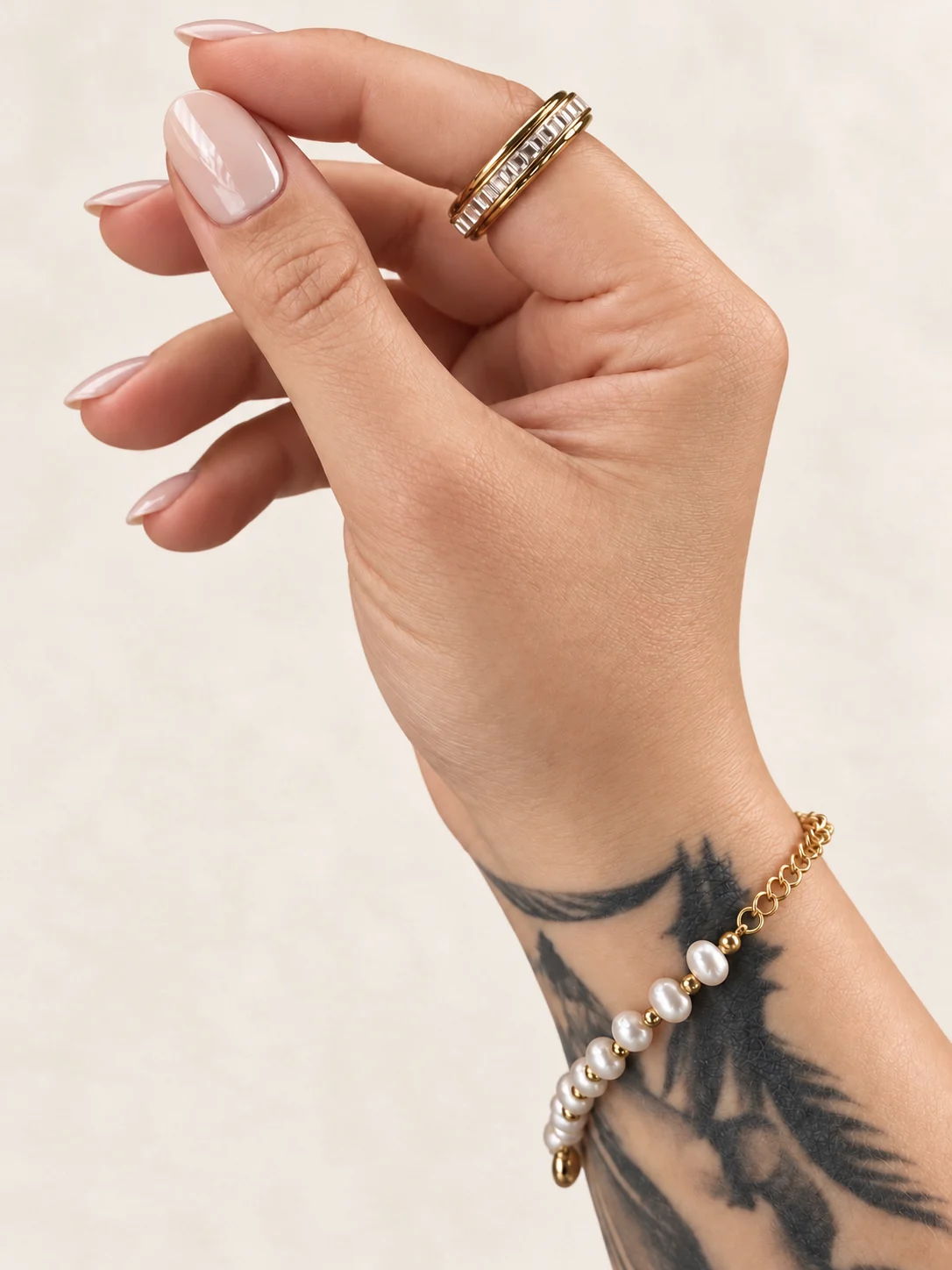 Perlenarmband und goldfarbener Ring an Sinas tätowierter Hand